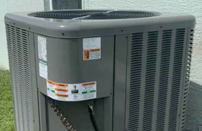 Outdoor air conditioning condenser beside a stucco home